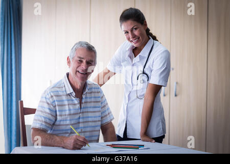 Portrait du docteur et senior man smiling pendant le dessin dans le dessin d'adresses Banque D'Images