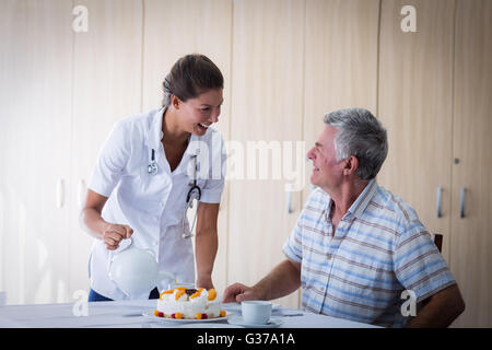 Femme médecin aînés célébration anniversaire de l'homme dans la salle de séjour Banque D'Images