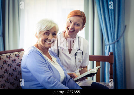 Smiling doctor helping senior woman pour lire un livre Banque D'Images