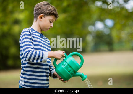 Garçon verser de l'eau d'arrosoir Banque D'Images