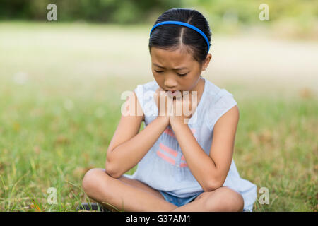 Upset girl sitting on grass Banque D'Images