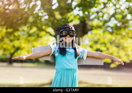 Smiling Girl standing with arms outstretched in park Banque D'Images