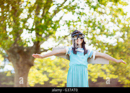 Smiling Girl standing with arms outstretched in park Banque D'Images