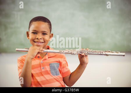 Portrait of smiling businesswoman playing flute in classroom Banque D'Images