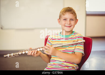 Portrait of smiling businesswoman playing flute in classroom Banque D'Images