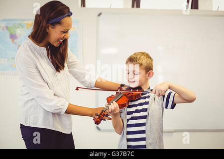 Aide aux enseignants un écolier de jouer un violon en classe Banque D'Images