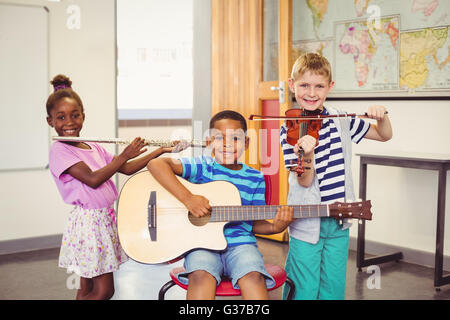 Portrait of smiling kids à jouer de la guitare, violon, flûte en classe Banque D'Images