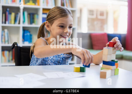 Smiling school girl Playing with building block in library Banque D'Images