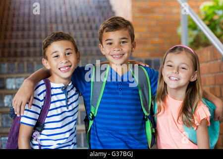 Les enfants de l'école souriant debout avec bras autour de Banque D'Images