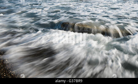 Les vagues de la mer s'écoule au-dessus d'un rocher de la mer la création d'une belle nature eau l'arrière-plan. Une longue exposition photo. Banque D'Images