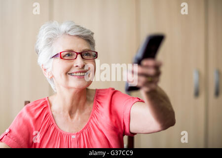 Senior woman à l'aide d'une télécommande Banque D'Images