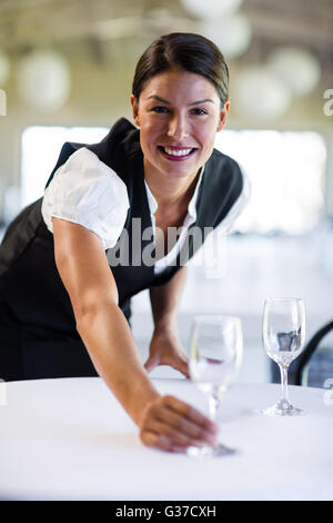 Portrait of smiling waitress setting the table Banque D'Images