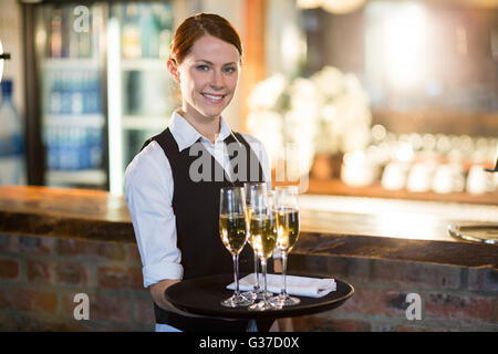 Portrait of waitress holding champagne flutesB avec plateau de service Banque D'Images