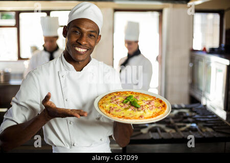 Portrait of smiling chef showing pizza Banque D'Images