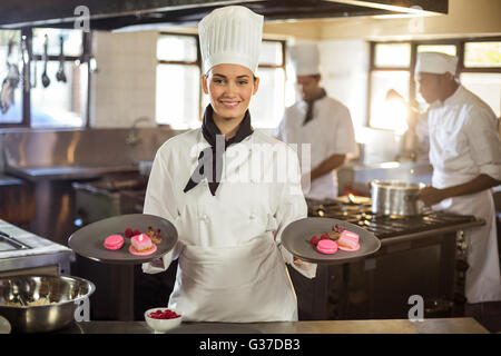 Portrait of smiling female chef presenting dessert plates Banque D'Images