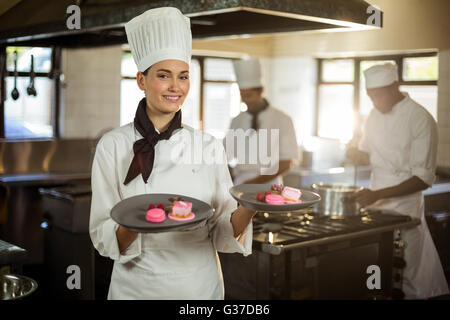 Portrait of smiling female chef presenting dessert plates Banque D'Images