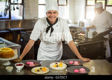 Portrait of smiling chef presenting dessert plates Banque D'Images