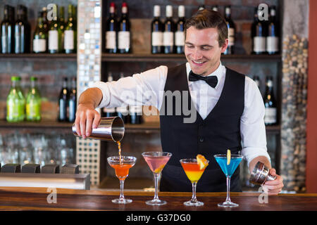 Bartender pouring orange une boisson dans le verre à martini Banque D'Images