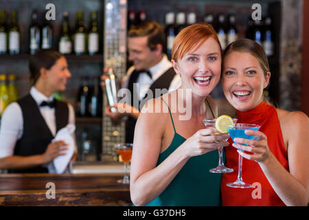 Portrait d'amis tenant un cocktail en face de comptoir bar Banque D'Images