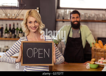 Portrait de deux serveurs occasionnels holding un conseil ouvert écrit Banque D'Images