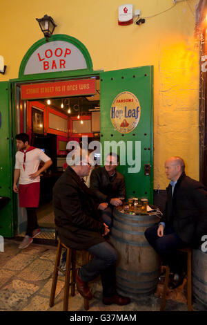 Les personnes qui boivent dans la ruelle à l'extérieur d'un bar rétro dans Strait Street à La Valette. Banque D'Images