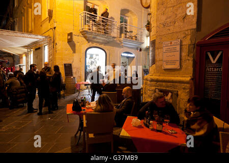 Bars et cafés set tables dans la ruelle connue sous le nom de rue du détroit à La Valette en soirée. Banque D'Images