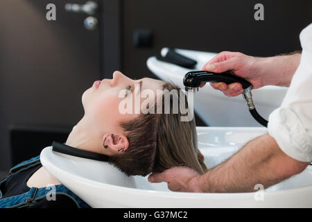 Les jeunes adolescentes dans le salon de coiffure le lavage des cheveux par les hommes de mains du coiffeur. Banque D'Images