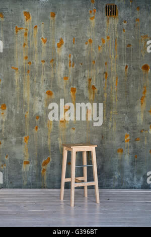 Tabouret de bar chaise sur mur de béton avec des points de rouille. Banque D'Images