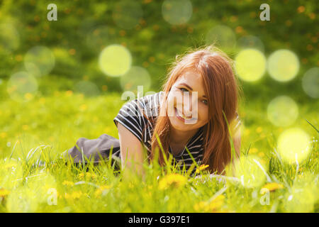 Red hair girl lying in grass Banque D'Images