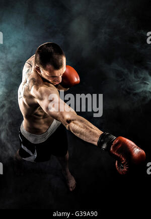 Kickbox musculaire ou muay thai boxe chasse dans la fumée. Banque D'Images