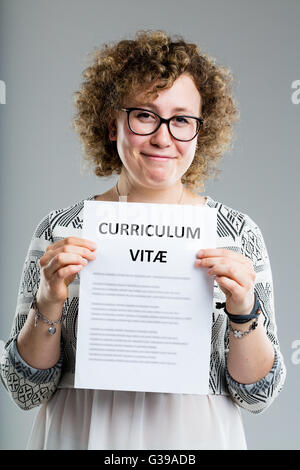 Femme bouclés sur un fond neutre montrant son curriculum vitae Banque D'Images