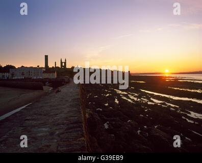 St Andrews, Fife : W & E extrémités de la cathédrale en ruine et la tour de la règle de St à la NW du mur du port avec un homme d'admirer le coucher du soleil. Banque D'Images