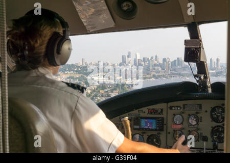 Femme pilote de l'hydravion en venant se poser sur le lac Union, Seattle avec l'horizon de la ville vue à travers la fenêtre du cockpit. Banque D'Images