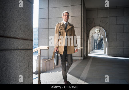 Homme d'entreprise en trench coat walking in cloître Banque D'Images