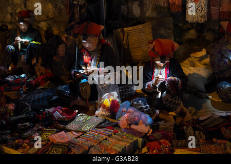 Dao rouge femmes fabriquent et vendent l'artisanat tribal à un marché de nuit à Sapa, province de Lao Cai, Vietnam Banque D'Images