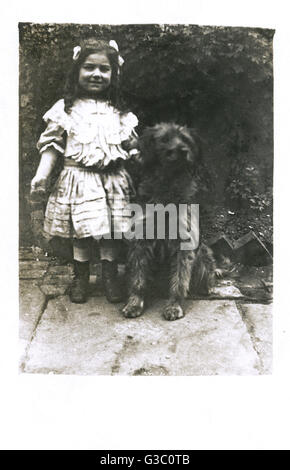 Petite fille avec un chien dans un jardin Banque D'Images