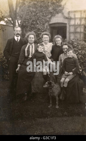 Famille de sept personnes avec un chien dans un jardin Banque D'Images