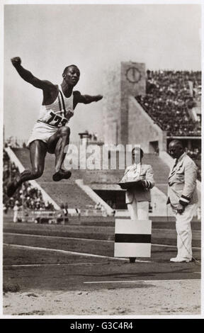 Jeux Olympiques de Berlin - Jesse Owens (1913-1980) au saut en longueur, la production de sa médaille d'or de saut de 26 pi 5 po (l'une des quatre médailles d'or qu'il a gagné à ce jeux). Date : 1936 Banque D'Images