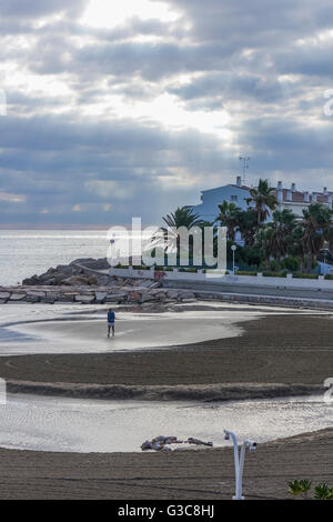 Homme seul marche sur une plage déserte Banque D'Images