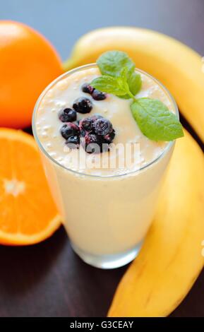 Smoothie sain avec de la banane, de l'orange et bleuets fruits décoré de feuilles de menthe fraîche Banque D'Images