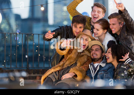 Jeunes adultes enthousiastes friends at rooftop party selfies Banque D'Images