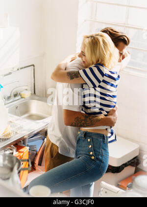 Jeune couple hugging in Cuisine de l'appartement Banque D'Images