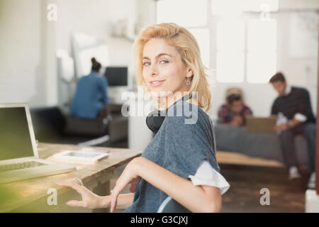 Portrait confiant female college student with headphones at laptop Banque D'Images