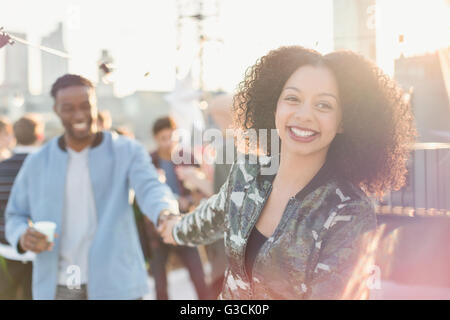 Smiling young couple holding hands at rooftop party Banque D'Images