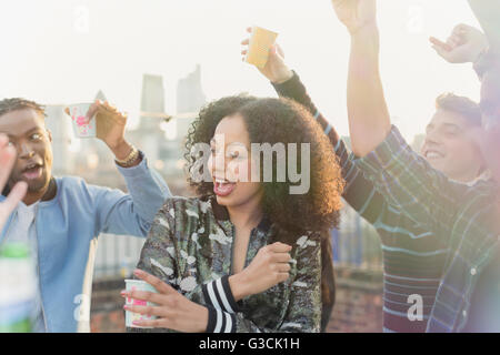 Jeune femme danser et boire at rooftop party Banque D'Images