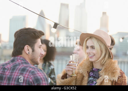 Jeune couple talking and drinking champagne at rooftop party Banque D'Images