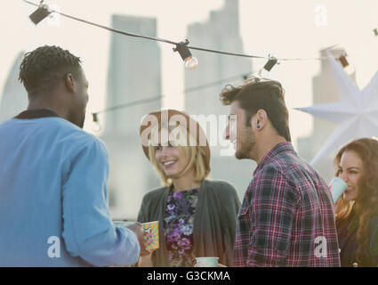 Amis parler des jeunes adultes et de boire at rooftop party Banque D'Images