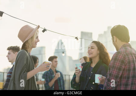 Les amis des jeunes adultes de boire et de parler at rooftop party Banque D'Images