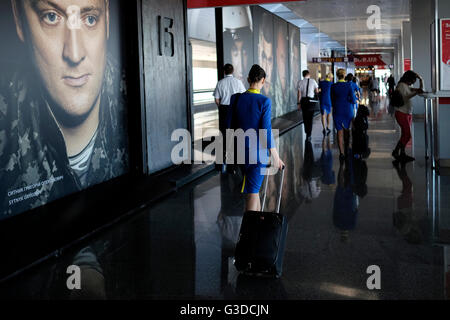 L'équipage des compagnies aériennes passe devant des affiches portant des portraits de soldats ukrainiens à l'aéroport international de Zhuliany à Kiev en Ukraine Banque D'Images