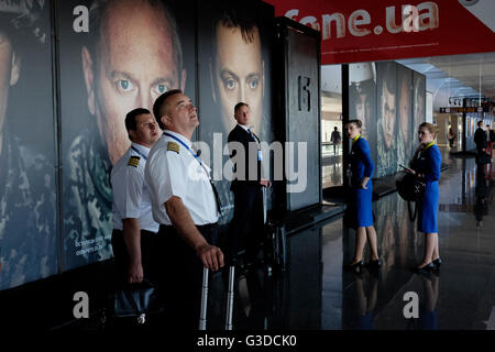 L'équipage de la compagnie aérienne Ukraine International Airlines se trouve à côté d'affiches portant des portraits de soldats ukrainiens à l'aéroport international de Zhuliany à Kiev en Ukraine Banque D'Images